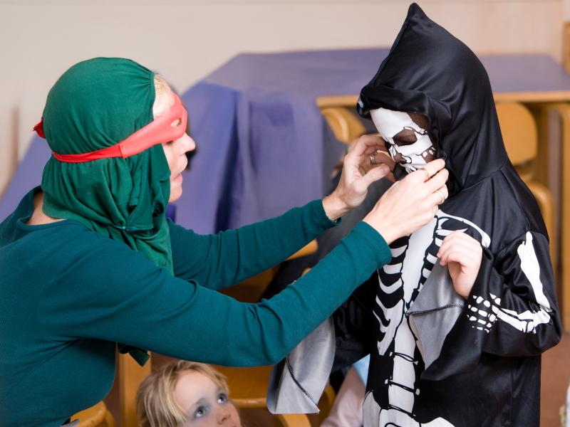 En person er i gang med at iklæde et barn et skeletkostume