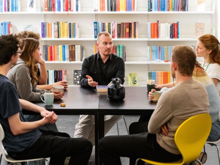 En gruppe mennesker sidder omkring et bord i biblioteket. 