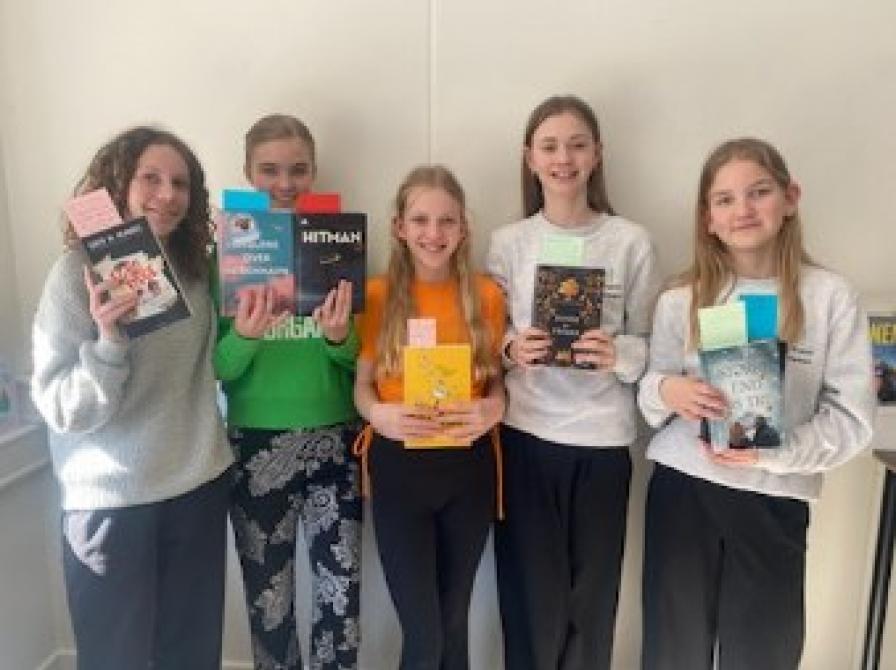 En gruppe piger står sammen med bøger i hænderne