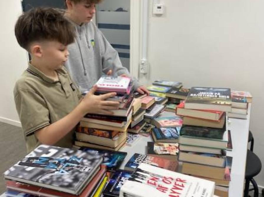 To elever står foran bunker af bøger